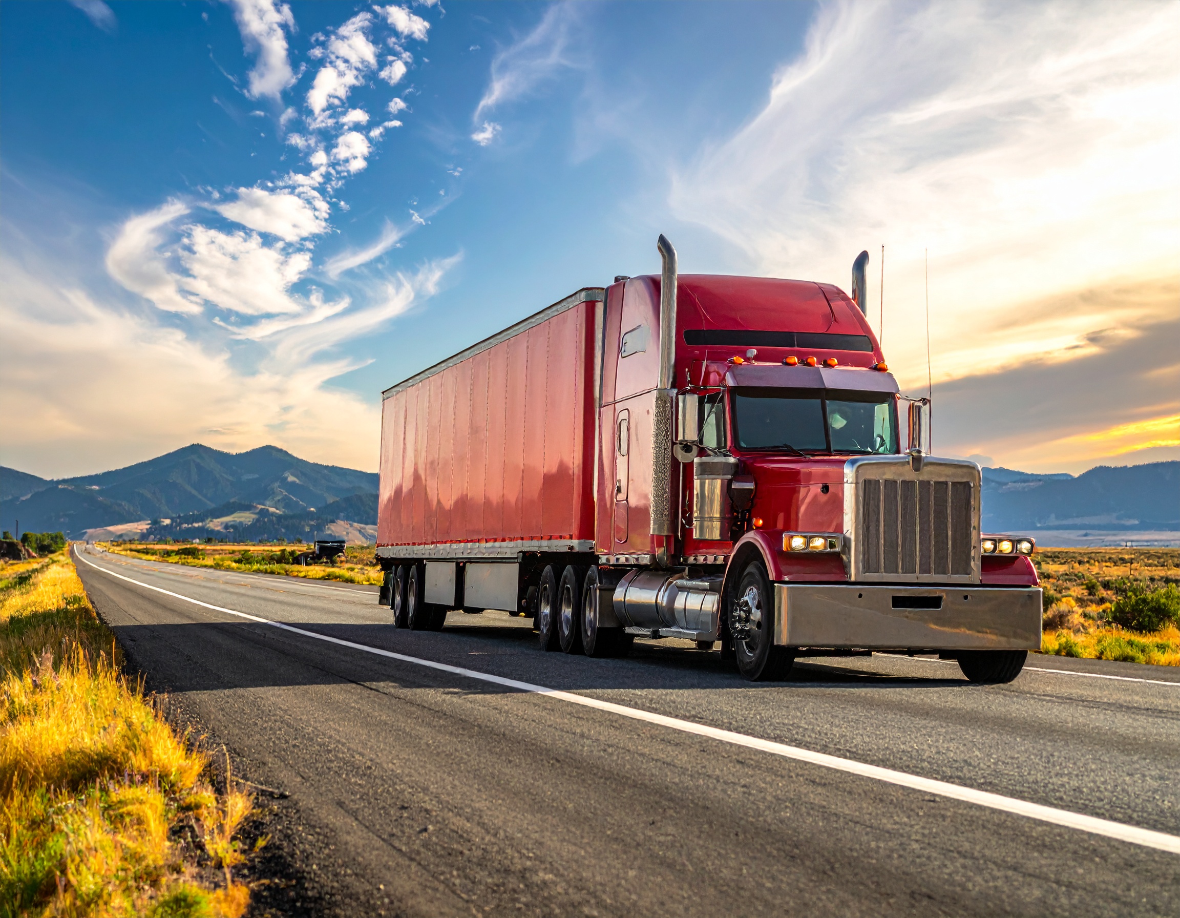 Semi truck driving on a highway at sunset